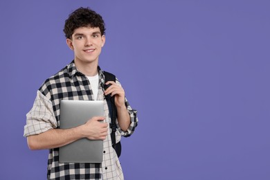 Photo of Portrait of student with backpack and laptop on purple background. Space for text