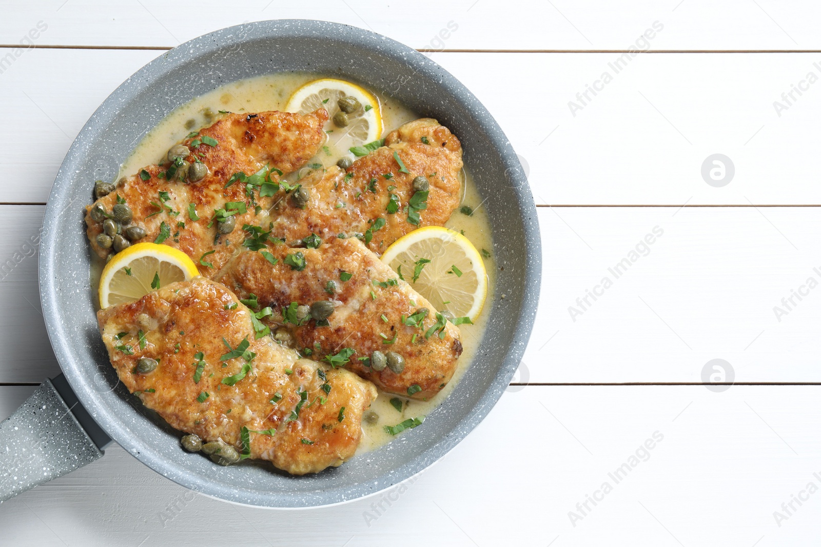 Photo of Delicious chicken piccata on white wooden table, top view. Space for text