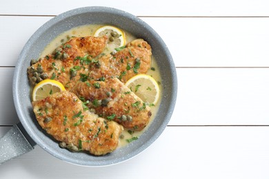 Delicious chicken piccata on white wooden table, top view. Space for text