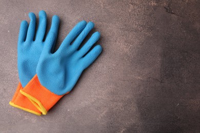 Pair of color gardening gloves on brown textured table, top view. Space for text