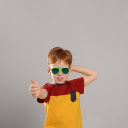 Photo of Cute little boy with sunglasses on light grey background