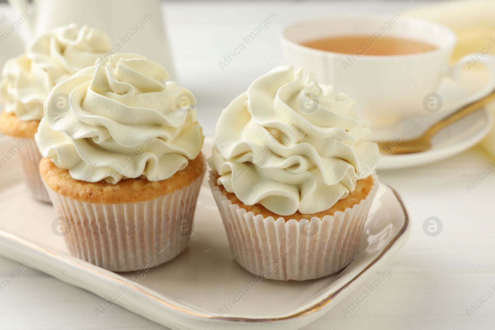 Photo of Tasty cupcakes with vanilla cream on white wooden table, closeup