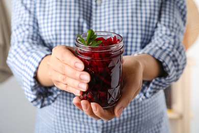 Photo of Woman holding glass jar with pickled beets, closeup