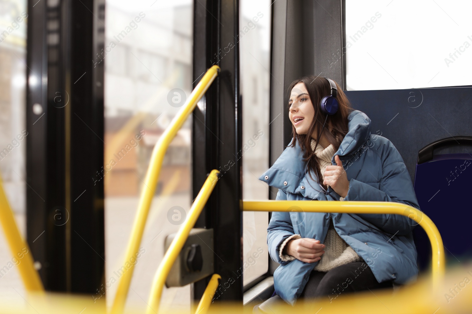 Photo of Young woman listening to music with headphones in public transport