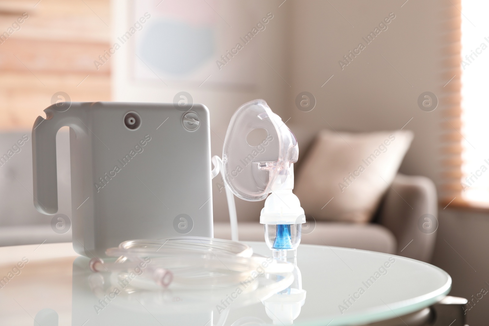 Photo of Modern nebulizer with face mask on white table indoors. Inhalation equipment