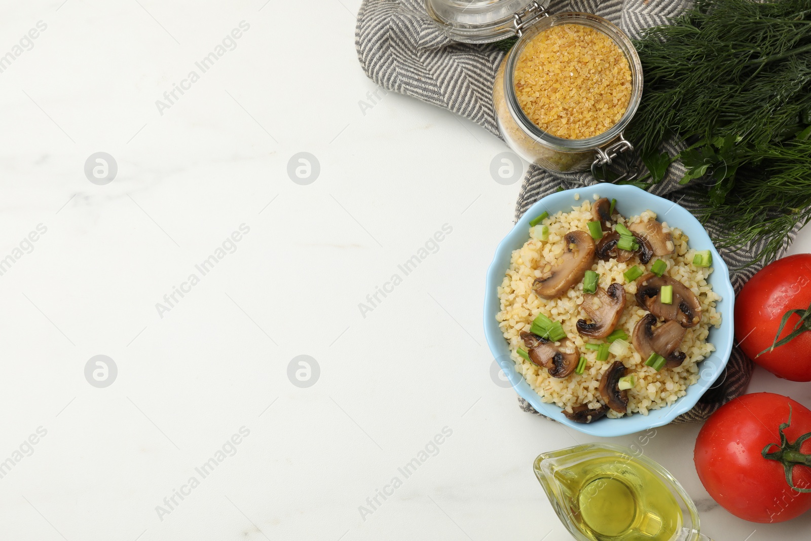 Photo of Delicious bulgur with mushrooms, green onion and other products on white marble table, flat lay. Space for text