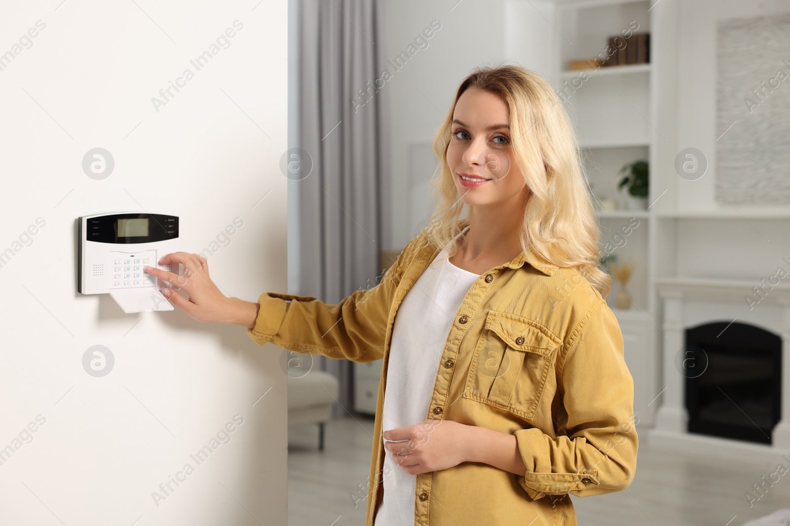 Photo of Woman entering code on home security system in room