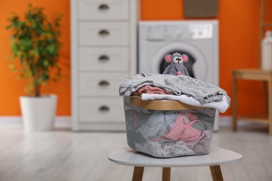 Laundry basket with baby clothes and toy on table in bathroom. Space for text