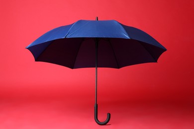 Photo of Stylish open blue umbrella on red background