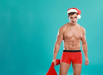 Photo of Sexy shirtless Santa Claus on blue background, space for text