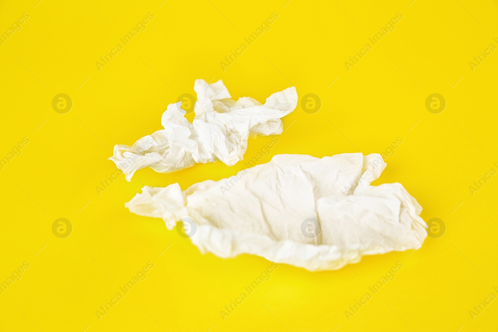 Photo of Used paper tissues on yellow background, closeup