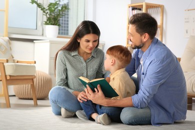 Happy family reading book together on floor in living room at home