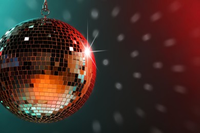 Photo of Shiny bright disco ball under color lights, space for text