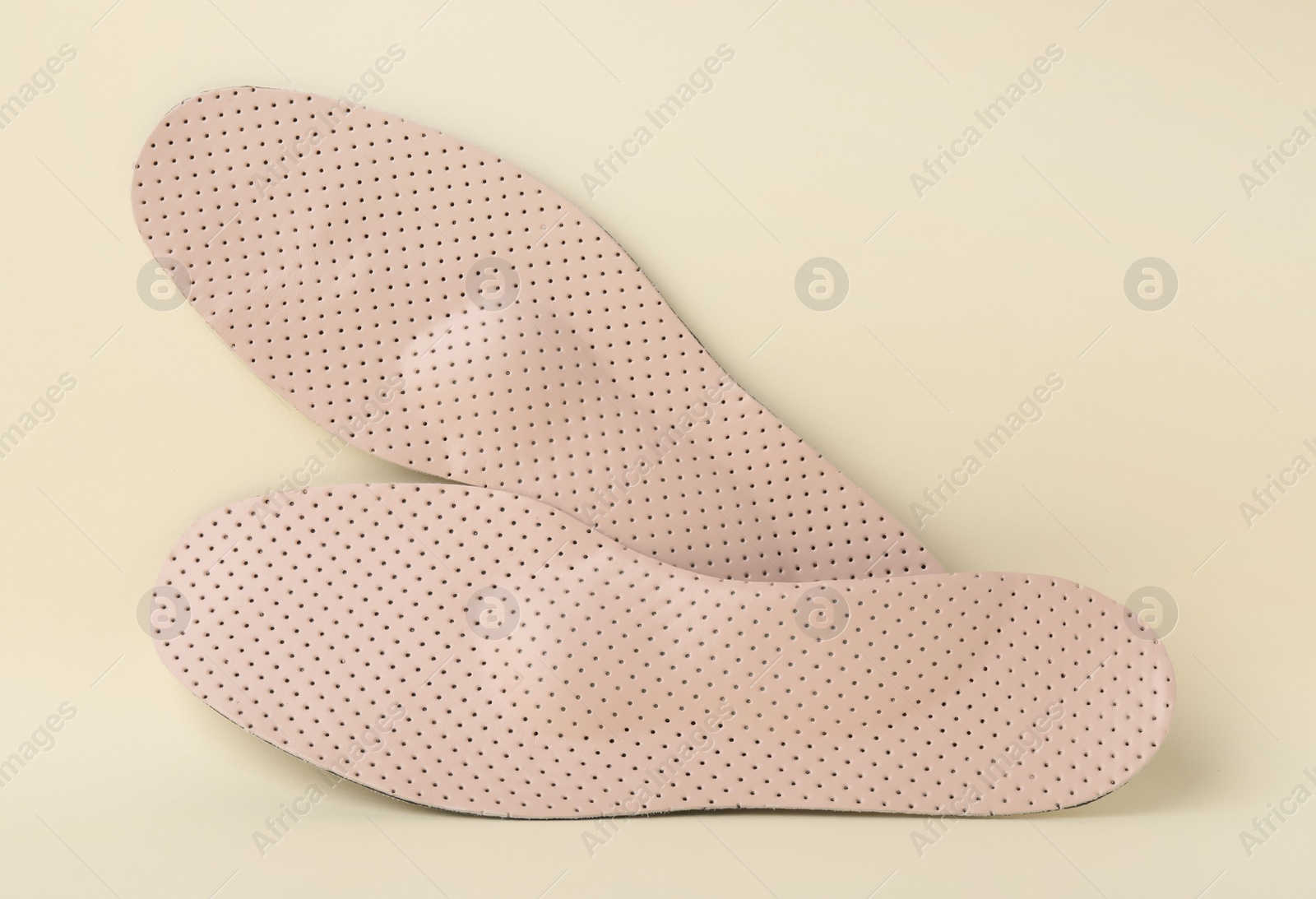 Photo of Comfortable orthopedic insoles on beige background, flat lay