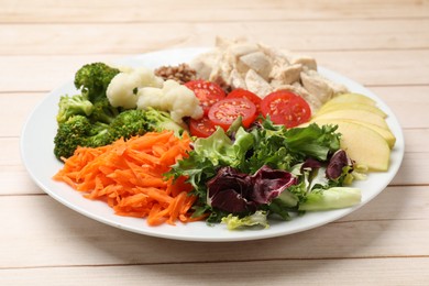 Photo of Balanced diet and healthy foods. Plate with different delicious products on light wooden table