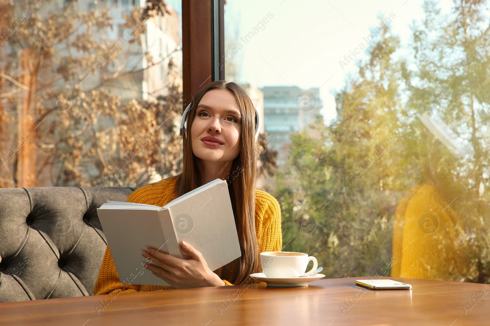 Photo of Woman listening to audiobook at table in cafe