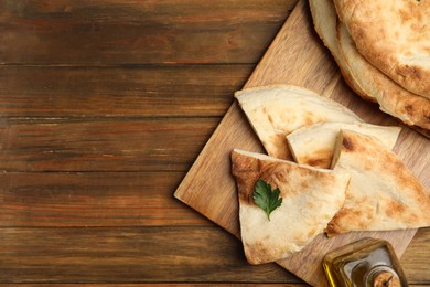 Photo of Cut fresh pita bread on wooden table, top view. Space for text