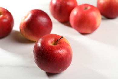 Photo of Fresh red apples with water drops on white table, closeup