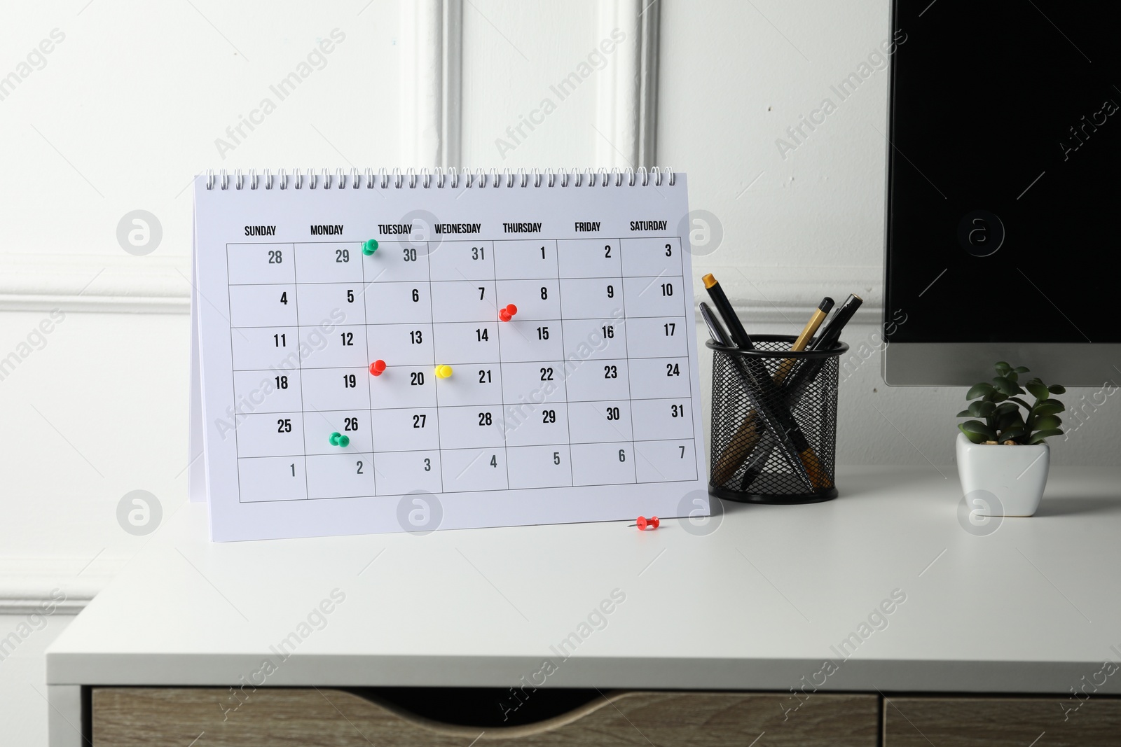 Photo of Timetable. Calendar with drawing pins and stationery on white table indoors