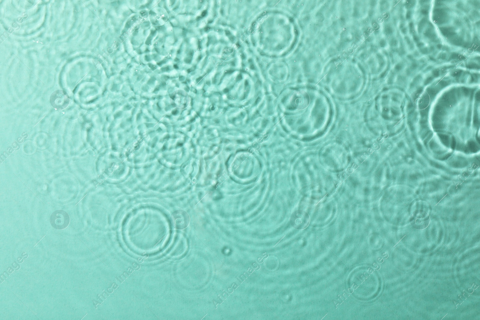 Photo of Clear water with rippled surface on turquoise background, top view