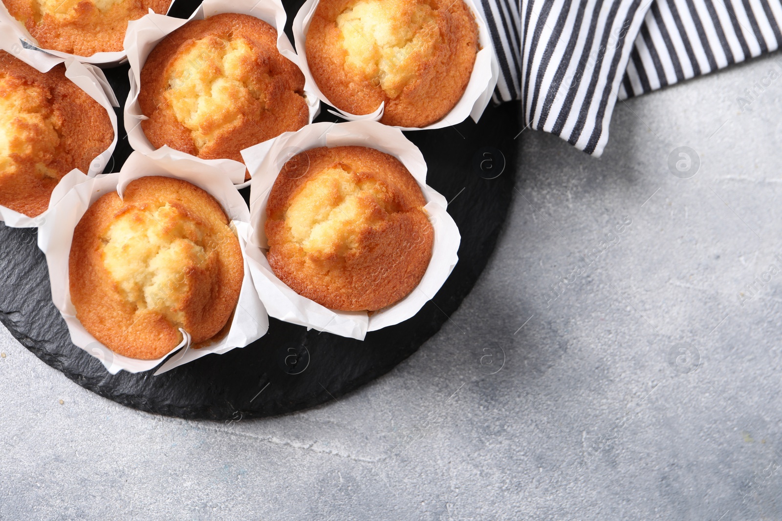 Photo of Delicious sweet muffins on light grey textured table, top view. Space for text