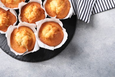 Delicious sweet muffins on light grey textured table, top view. Space for text