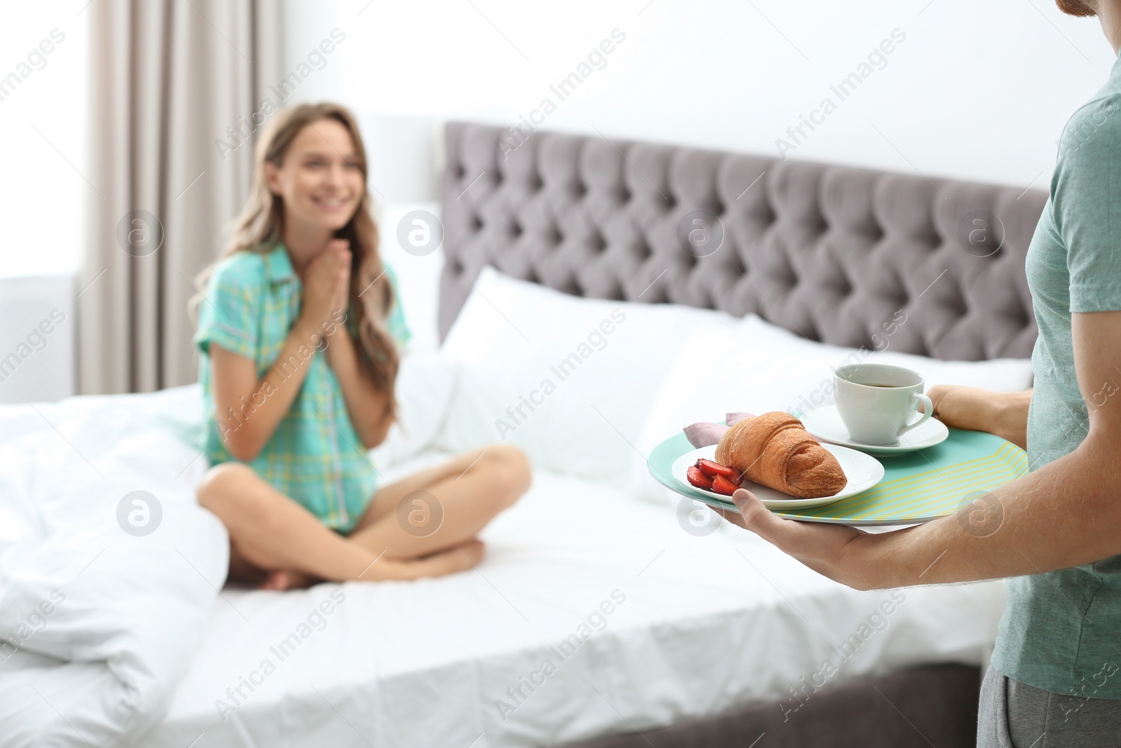 Photo of Young man bringing romantic breakfast to his girlfriend in bed at home