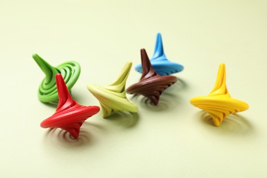 Photo of Many colorful spinning tops on green background, closeup