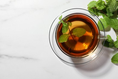 Photo of Cup of aromatic herbal tea with mint on white marble table, flat lay. Space for text
