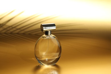 Photo of Luxury women's perfume. Sunlit glass bottle on golden background, space for text