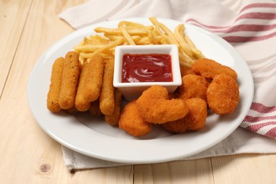 Photo of Plate with tasty ketchup, French fries, chicken nuggets and cheese sticks on wooden table, closeup