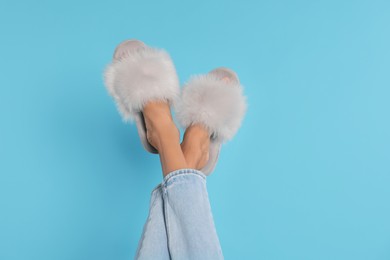 Photo of Woman in fluffy slippers on light blue background, closeup