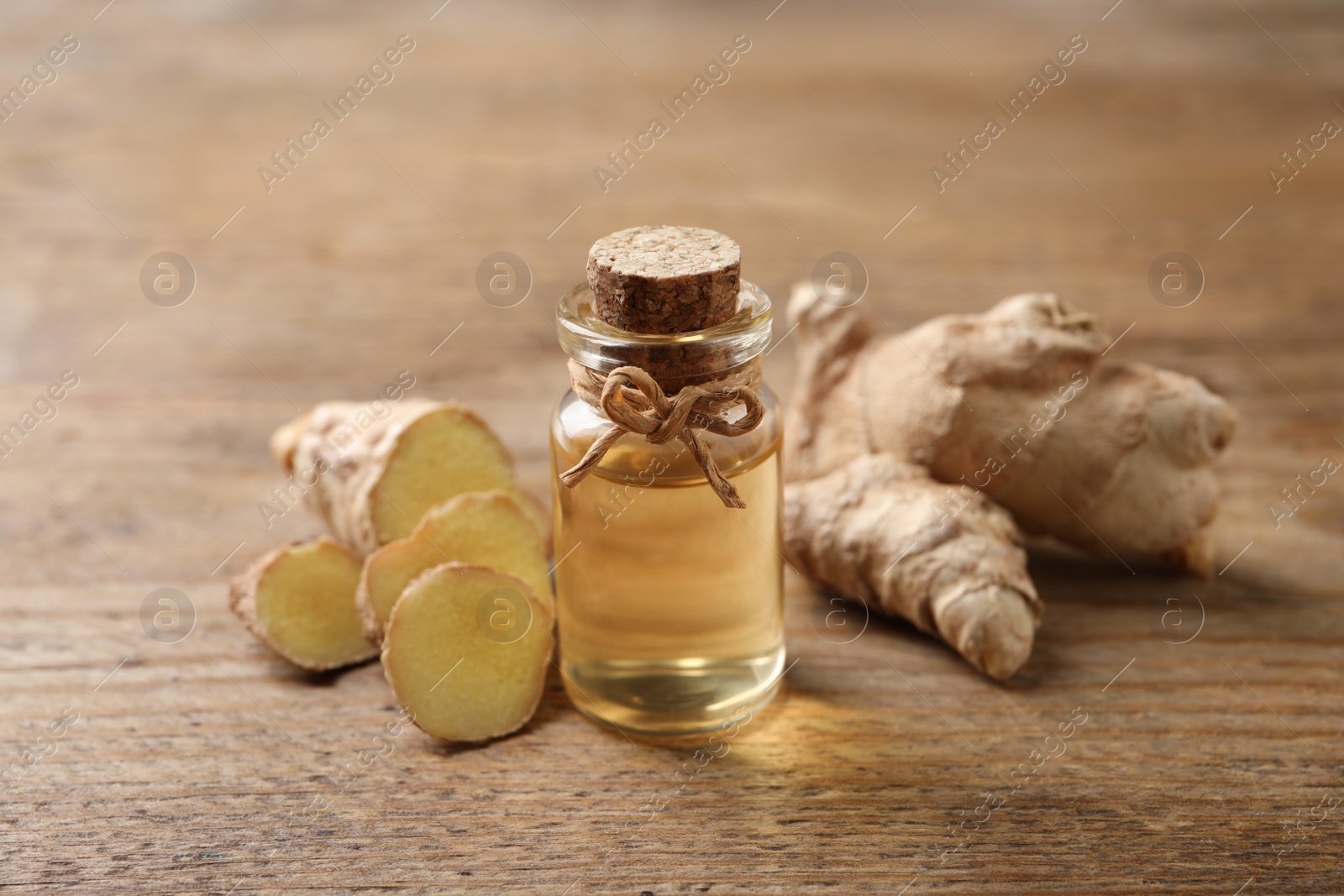 Photo of Ginger essential oil in bottle on wooden table