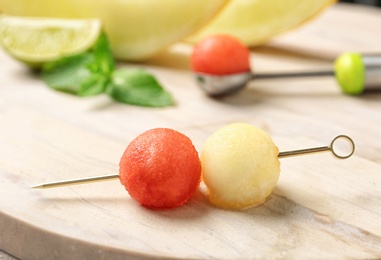 Photo of Cocktail stick with melon and watermelon balls on wooden table
