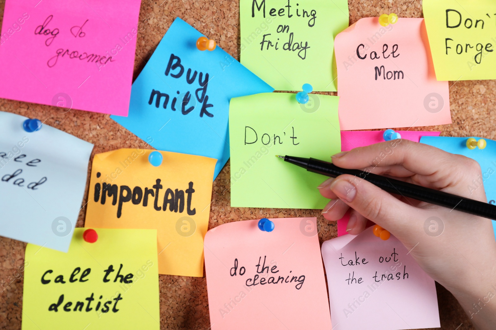 Photo of Woman writing paper note pinned to cork board, closeup