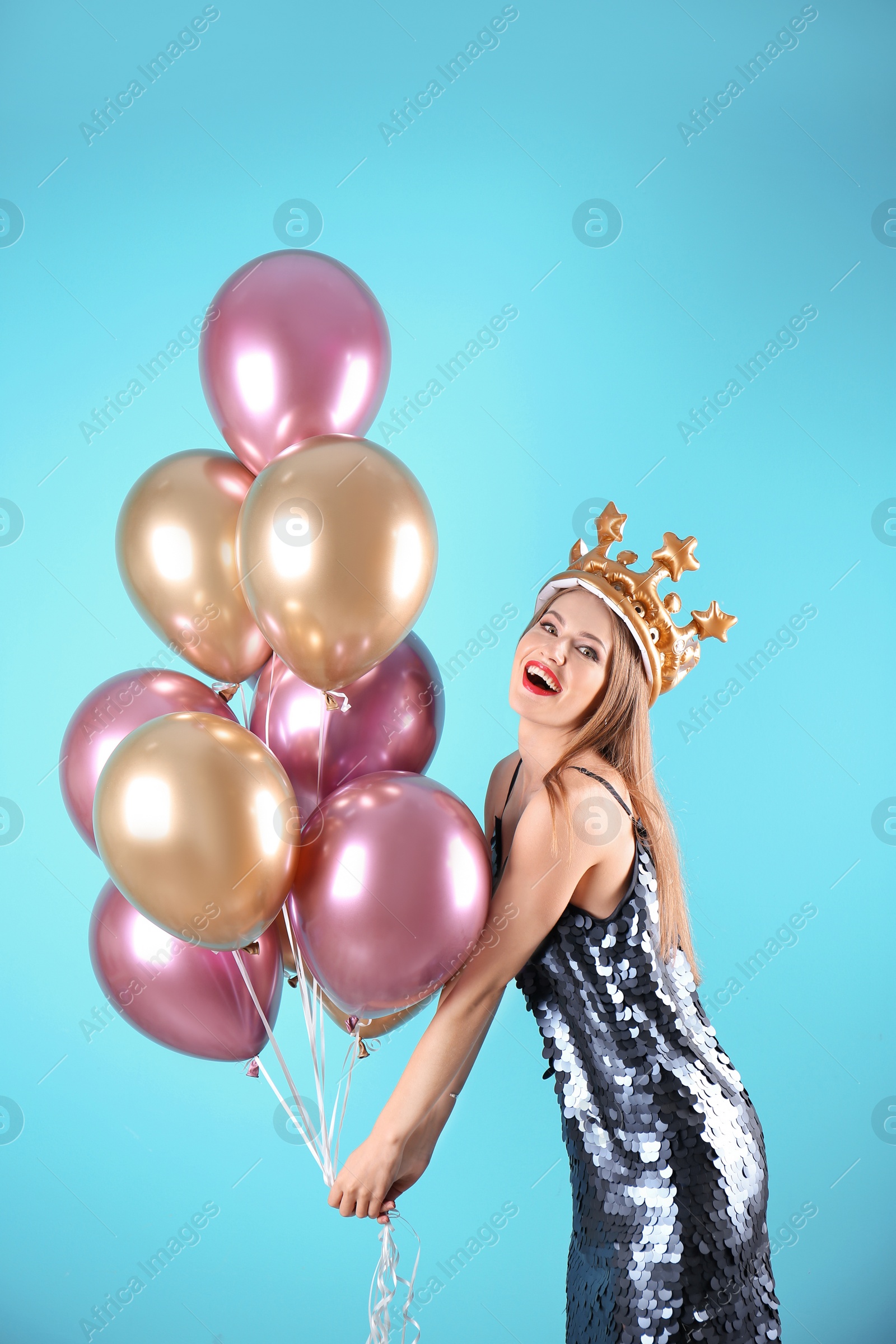 Photo of Young woman with crown and air balloons on color background