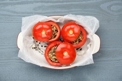 Photo of Uncooked stuffed tomatoes with minced beef, bulgur and mushrooms in baking dish on grey wooden table, top view
