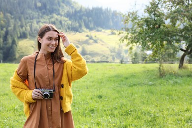 Photo of Happy woman with camera on meadow in mountains