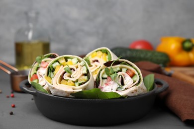Photo of Delicious sandwich wraps with fresh vegetables on grey table, closeup