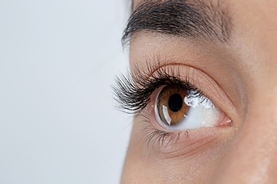 Photo of Young woman with beautiful eyelashes on gray background, closeup view