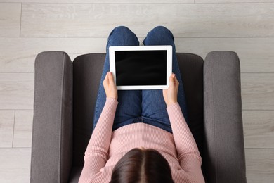 Photo of Woman working with tablet in armchair, top view