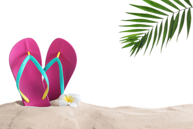 Photo of Pink flip flops and plumeria flower on sand against white background, space for text. Beach objects