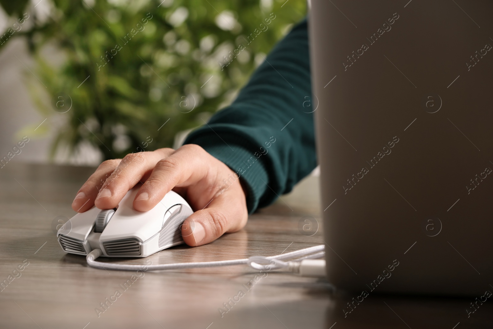 Photo of Man using computer mouse with laptop at table, closeup