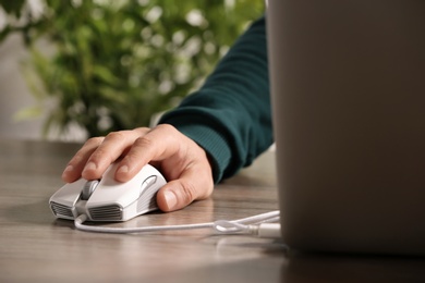 Photo of Man using computer mouse with laptop at table, closeup