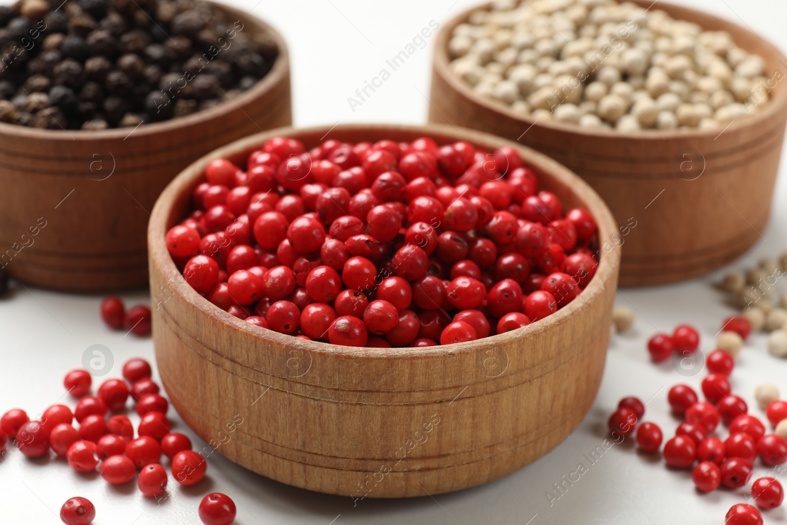 Photo of Aromatic spice. Different peppers in bowls on white table, closeup