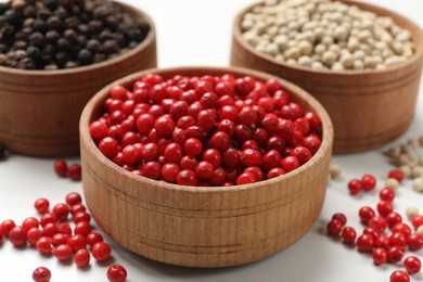 Photo of Aromatic spice. Different peppers in bowls on white table, closeup