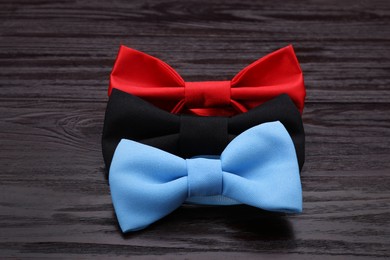 Different stylish bow ties on wooden table