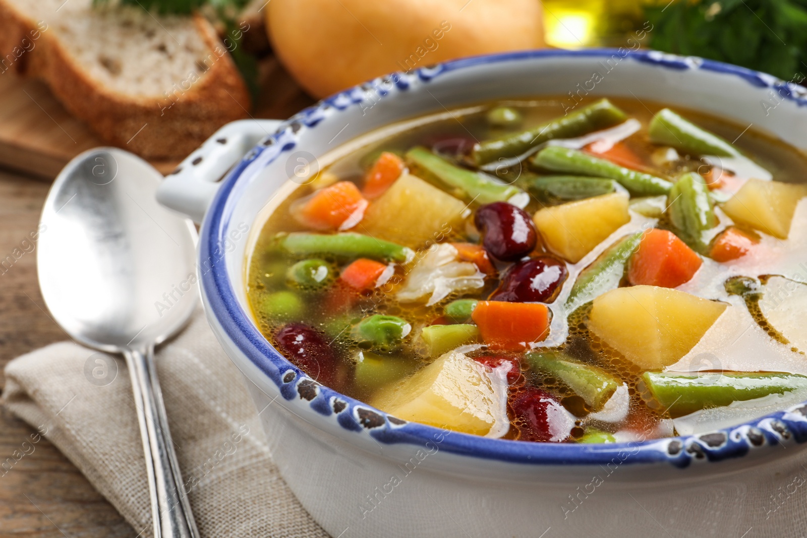 Photo of Bowl of tasty turnip soup with napkin and spoon on table, closeup