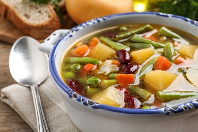 Photo of Bowl of tasty turnip soup with napkin and spoon on table, closeup