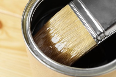 Dipping brush into can with varnish on table, closeup